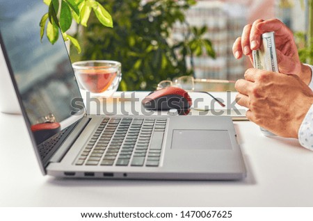 Men's hands doing work on a laptop in a modern workplace on the background of the window. Low depth of field as corporate background. Close up.