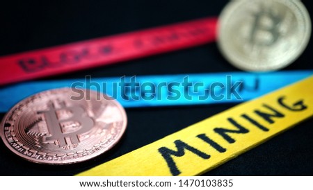 bitcoin gold coin and blurry copper bitcoin coin among wooden sticks of various colors with various writings on a black background, in macro view
