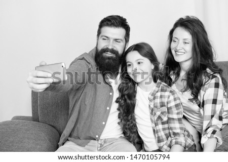Family spend weekend together. Use smartphone for selfie. Friendly family having fun together. Mom dad and daughter relaxing on couch. Family posing for photo. Capture happy moments. Family selfie.