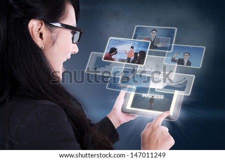 Businesswoman excited looking at success pictures on electronic tablet