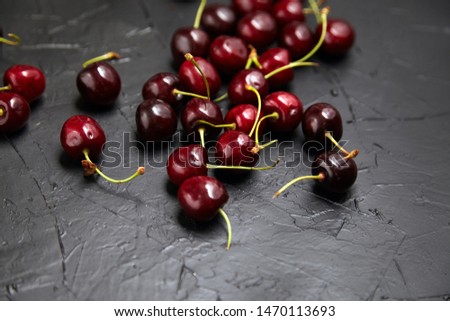Ripe cherries scattered on a black table. Red fresh berries on black stone table