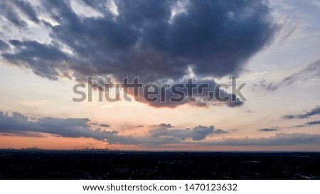 dark colorful aerial sunset, high up above the horizon with the sun hiding or being blocked by the dark evening clouds