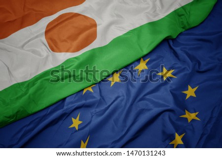 waving colorful flag of european union and flag of niger. macro