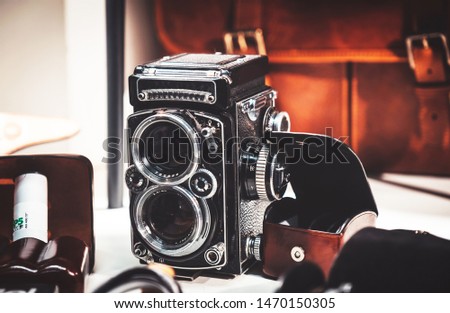 Old twin lens reflex camera and leather equipment in front of the brown leather handbag. Gentleman style photography.
Analog photography machine.

