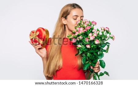 Attractive blonde woman with big bouquet of roses and gift box. Holidays and gifts concept. Women's day