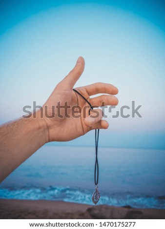 Pendant in hand on beach and sea background, Hand on sea background.