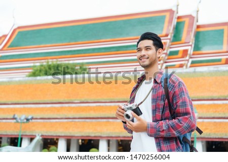 Asian man tourist walk taking photo with film camera  at Wat Suthat Thepwararam Ratchaworawihan Bangkok, Thailand in the summer time