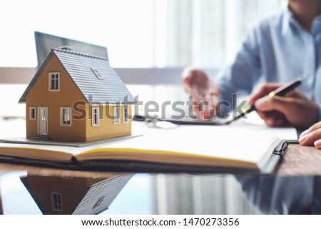 House model and business Insurance authorities showing an insurance policy and dealing the policyholder must to sign.