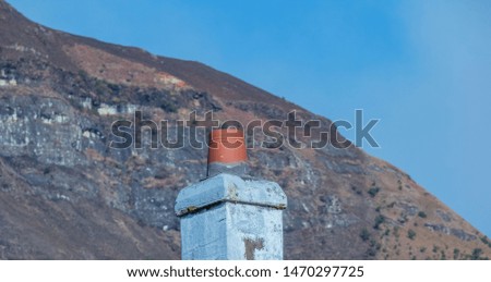 An old chimney isolated against a mountain and blue sky background image with copy space in landscape format