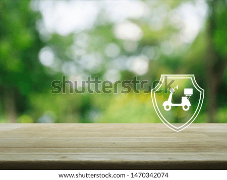 Motorcycle with shield flat icon on wooden table over blur green tree in park, Business motorbike insurance concept