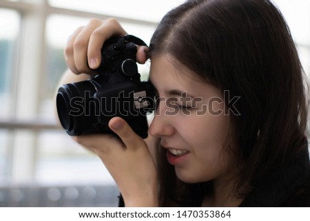 A young woman holds in her hands a camera and shoots, close-up.