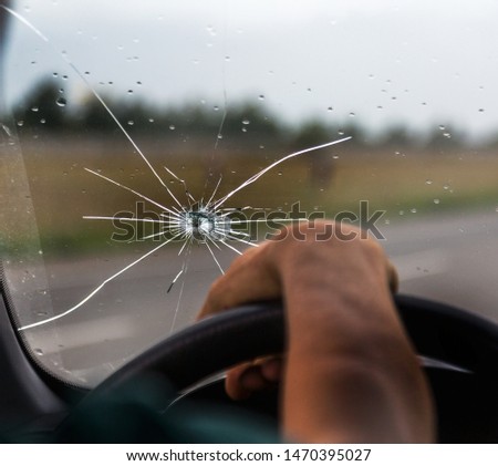 Broken windshield of a car. A web of radial splits, cracks on the triplex windshield. Broken car windshield, damaged glass with traces of oncoming stone on road or from bullet trace in car glass Royalty-Free Stock Photo #1470395027