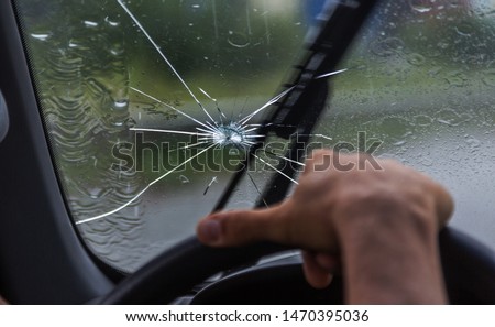 Broken windshield of a car. A web of radial splits, cracks on the triplex windshield. Broken car windshield, damaged glass with traces of oncoming stone on road or from bullet trace in car glass Royalty-Free Stock Photo #1470395036