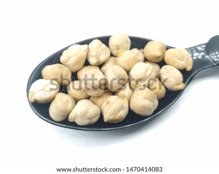 A picture of brown chickpeas on black spoon