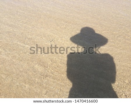 human shadow on brown beach sand and wave