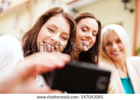 holidays and tourism concept - beautiful girls taking selfie in outdoor cafe in city