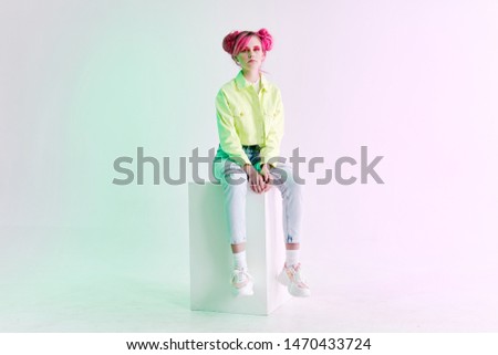 woman with pink hair sits on a cube