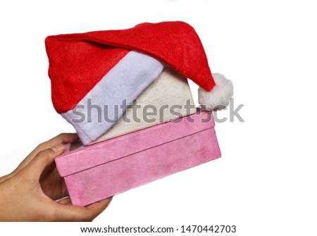 Hand holding present box with santa clause hat on top in white isolated background