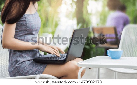 Young asian woman placed the laptop on the lap and working in outdoor garden