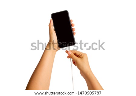 Women's hands plugging charger in a smart phone on white background