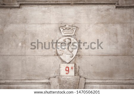The Castle coat of arms family crest plaque with lion and crown above the original Medieval Roman Castle entrance tower arch engraved on a stone wall in Brescia, Lombardy, Italy. Heritage. Antique. 