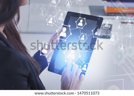 Unrecognizable woman with tablet computer using social connection interface in blurred office. Concept of HR and social media. Toned image double exposure