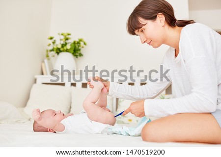 Mother controls temperature in her baby with rectal thermometer Royalty-Free Stock Photo #1470519200