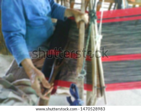 blurred picture  the local Thai woman weaving the black and red cloth with the hand loom.  