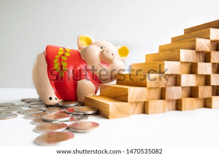 Red piggy bank saving money with coins pile and wood graph.