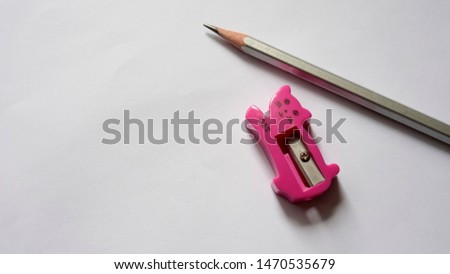 Pink pencil sharpener and pencil on a white background.                           
