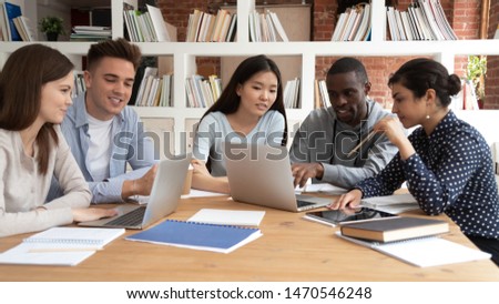 Focused african american guy showing important information to indian and asian teammates on computer screen. Group of mixed race students working together on school project, doing research at library. Royalty-Free Stock Photo #1470546248