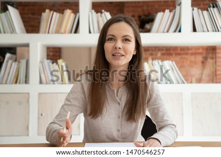 Happy attractive young hr manager sitting at table, holding video call job interview with potential employee. Smiling millennial female professional recording educational video for online course. Royalty-Free Stock Photo #1470546257