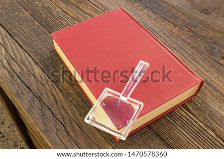 Magnifying glass with book on wooden table