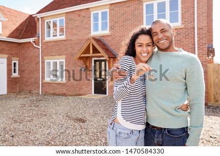Portrait Of Couple Holding Keys Standing Outside New Home On Moving Day Royalty-Free Stock Photo #1470584330