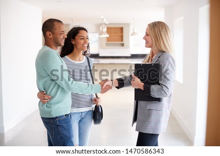 Female Realtor Shaking Hands With Couple Interested In Buying House Royalty-Free Stock Photo #1470586343