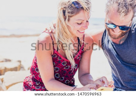 A couple in a relationship having a good time outdoors with a smartphone in summer holidays.