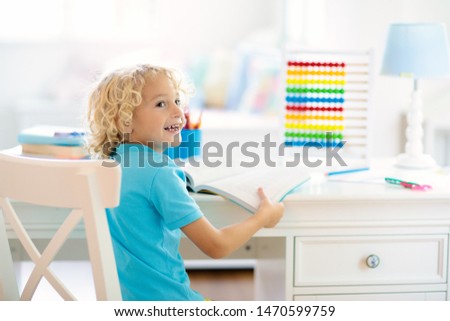 Child drawing rainbow. Kid painting at home. Little boy doing homework after school. Kids desk with abacus in white sunny bedroom. Children study, learn to read and write. Bedroom for young student.