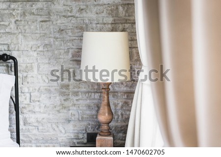 A lamp in a room corner with concrete wall.