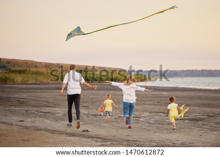 Happy family, father and mother and two children launch a kite on nature at sunset. 