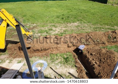 The excavator digs a trench in a private area to lay the electrical cable to the house.