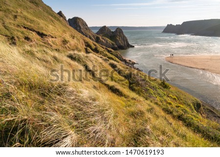 Beautiful Summer evening sunset beach landscape image at Three Cliffs Bay in South Wales 