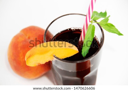glass cup with cherry juice, green mint leaves and orange peaches