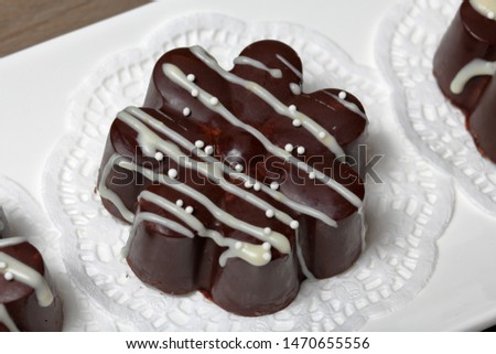 Chocolate dessert in the shape of a flower. Dark chocolate coated. Garnished with white chocolate and sprinkles.