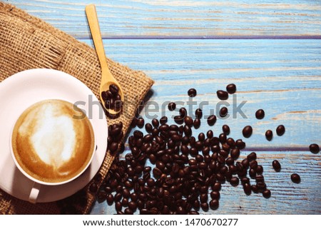 The top view of the coffee cup and roasted coffee beans on a blue painted wood floor