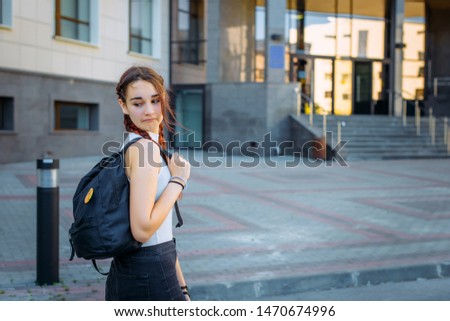 Concept of training and education. High school concept. Young beautiful cheerful student grimaces and has fun on the way to College.