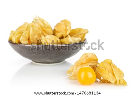 Lot of whole fresh orange physalis one is in the front in dark ceramic bowl isolated on white background
