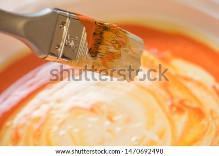 white and orange paint mixed with a brush to paint the walls