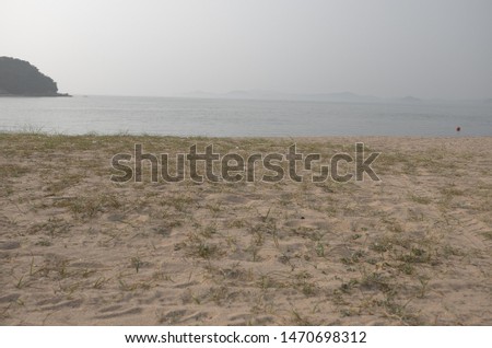 A picture of Tranquil summer beach on a slightly hazy day.