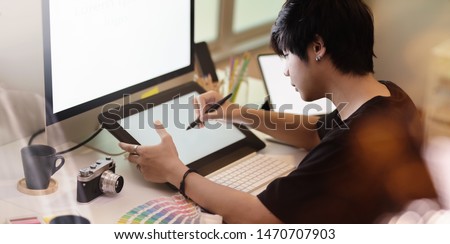 Close-up view of motivated photographer drawing on tablet in his minimal workplace 