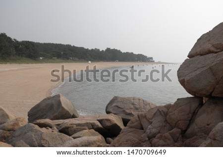A picture of tranquil summer beach with rocks on a slightly hazy day.
